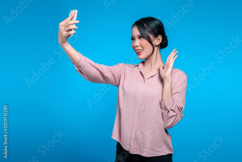 Smiling Asian Woman Waving During a Video Call on Her Smartphone