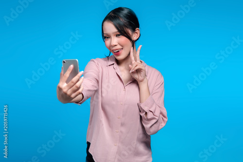 Smiling Asian Woman Taking a Selfie and Showing Peace Sign