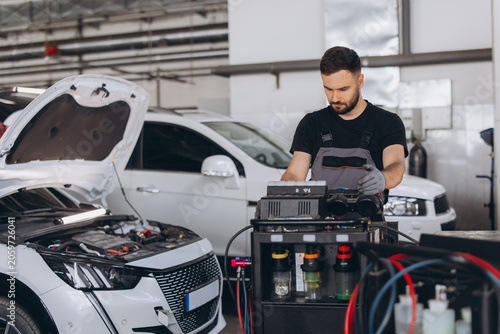 фотографія Young male mechanic performing vehicle maintenance, checking and recharging car
