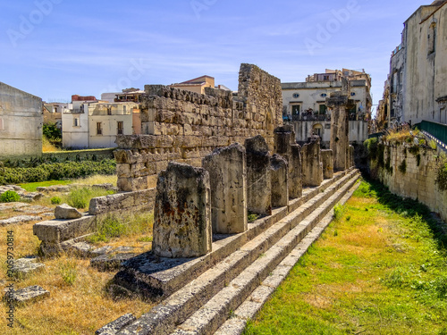 Impressive perspective of the stone colonnade and ancient steps of the Temple of Apollo in Ortigia, Syracuse, Italy. Historic Greek ruins under a sunny blue sky in Sicily.