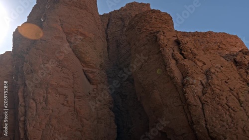 A dramatic low-angle shot capturing the intense morning sun breaking directly behind the rugged, monumental limestone mountain cliffs of the Theban Hills in Luxor, Egypt.