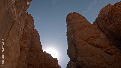 A dramatic low-angle shot capturing the intense morning sun breaking directly behind the rugged, monumental limestone mountain cliffs of the Theban Hills in Luxor, Egypt.