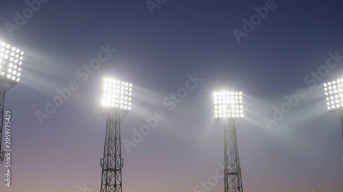Powerful stadium lights illuminating the evening sky with bright beams