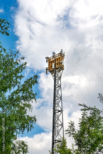 A telecommunication tower with antennas stands against a cloudy sky.