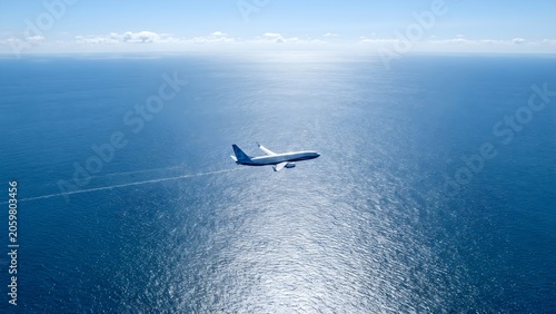 Commercial Airplane Flying Over Vast Blue Ocean Under Clear Sky.