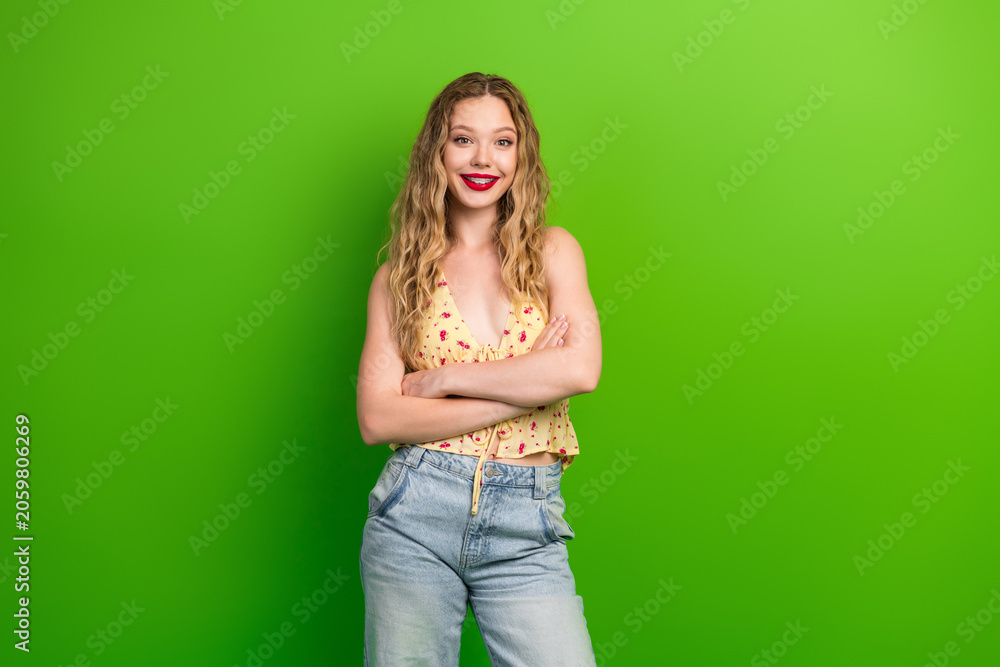 Naklejka premium Casual stylish young woman with blonde hair posing in front of green background smiling confidently for lifestyle fashion image