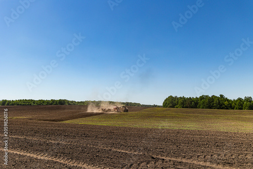 Canvas-taulu Modern tractor with seeding equipment working on agricultural field