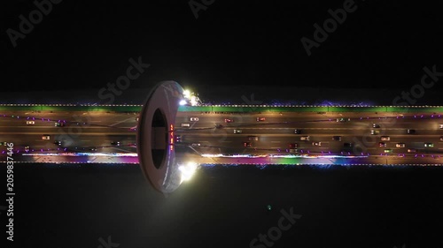 Overhead panning drone shot of traffic driving over illuminated bridge at night in Guangzhou, China