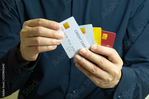 Close up of hand human holding multiple color credit cards, choosing a red card for payment, concept of consumerism, financial management, debt and cashless society and saving money	