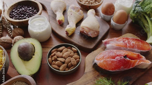 Slow camera movement along healthy food ingredients laid out on a wooden background: meat, fish, grains and vegetables.