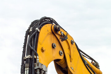 Yellow excavator arm with hydraulic hoses against cloudy sky construction and rebuilding business closeup photo background