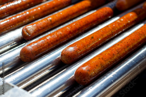 Fotografi Hot dogs cooking on roller grill, fast food and concession stand concept, quick meal preparation, american cuisine