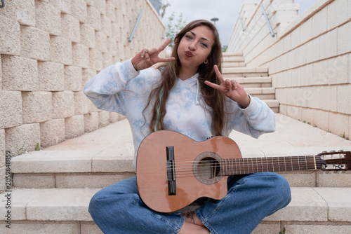 Young woman showing peace signs with acoustic guitar