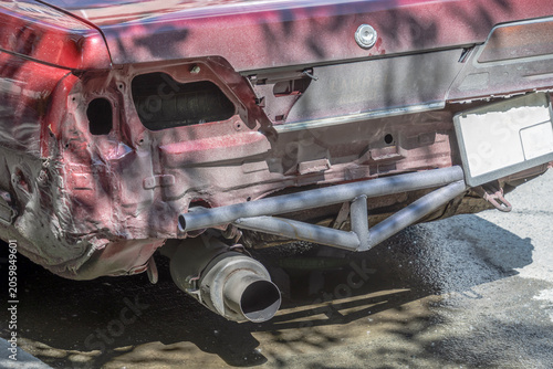 An abandoned broken-down car stands in the parking lot on a summer day