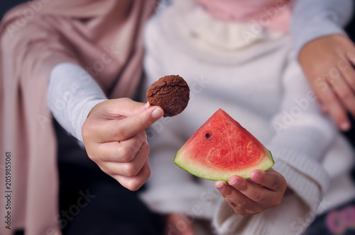 Foto Close up of two young Muslim girls wearing hijabs holding a chocolate cookie and