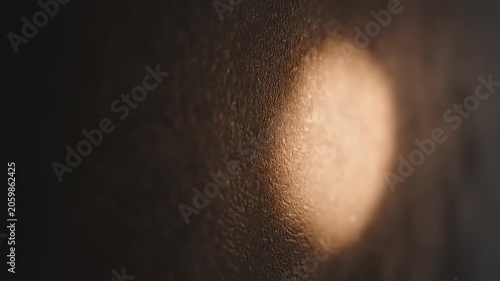 A close-up shot of a person's face with a light shining on their cheek in a dark environment