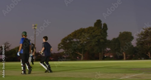 Cricket partners cheering after wicket fall bowler running in bowling hitting stumps under lights