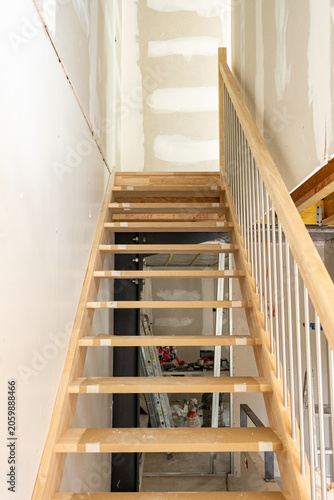 Escalier en cours de rénovation dans un intérieur en travaux, illustrant un chantier de construction avec des matériaux et finitions en transformation.