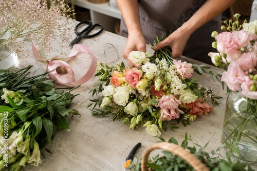 Quadro su tela Florist hands arranging fresh seasonal flowers on worktable