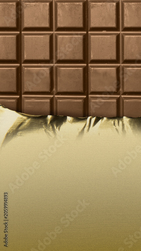 A vertical close-up of a classic milk chocolate bar, partially unwrapped from its elegant gold foil packaging