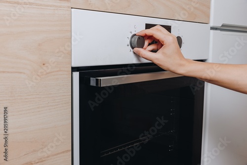 Obraz na plátne Oven control knob being turned on a modern kitchen appliance with a sleek design