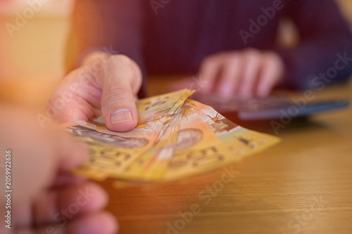 Obraz na plátne Businessman hands giving money Australian dollars, People handing over Australia
