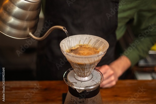 Obraz na płótnie A close up of a barista pouring hot water from a gooseneck kettle into a coffee