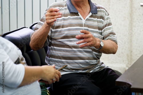 Unrecognizable senior male explaining and making hand gestures while talking to a colleague sitting in a leather chair. Corporate debate or casual conversation indoors. Photo