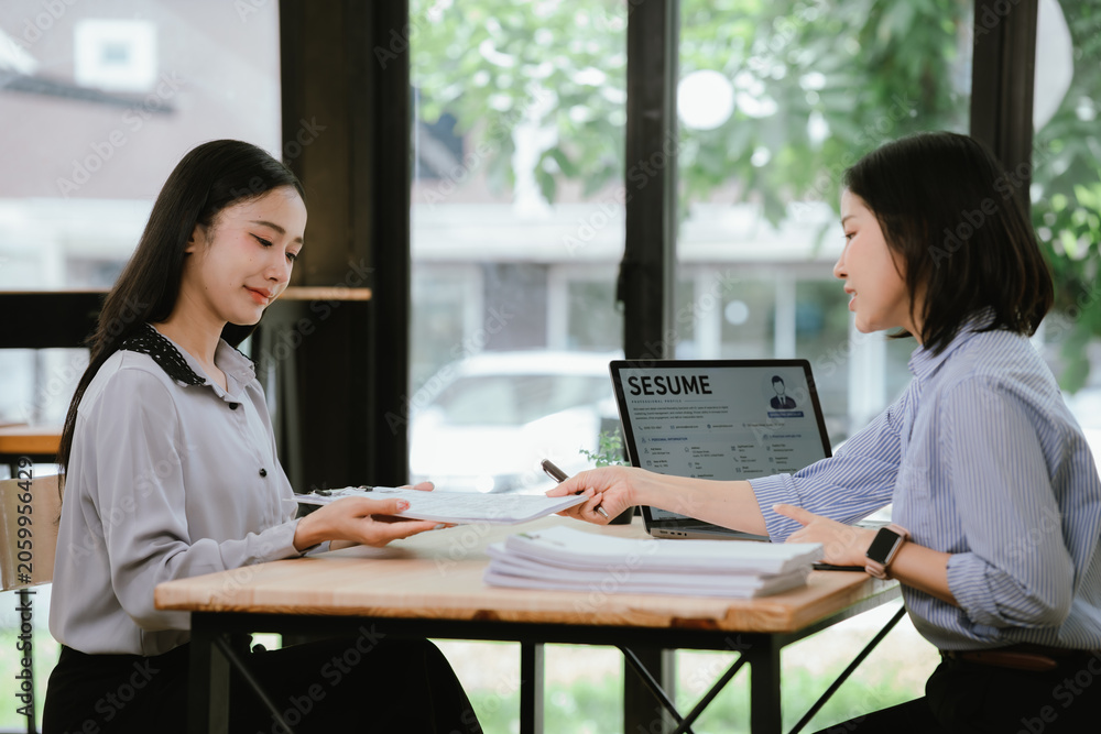 Obraz premium HR manager interviewing a job candidate across a desk, discussing qualifications and experience during a recruitment meeting in a modern office environment.