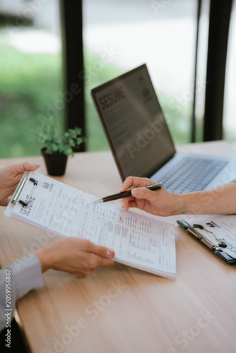 Photos HR manager reviewing and discussing a candidate’s resume during a job interview, assessing qualifications and experience for a recruitment decision