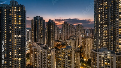 Dense cluster of illuminated high-rise apartment towers at dusk with a glowing city skyline and colorful sunset sky