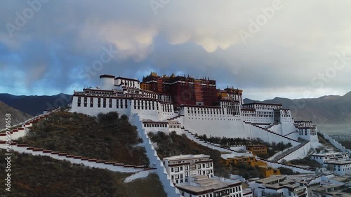 Aerial view of the Potala Palace at sunrise in Lhasa, Tibet, China, with the historic palace on the hill overlooking the city, surrounded by mountains and morning mist under golden light.