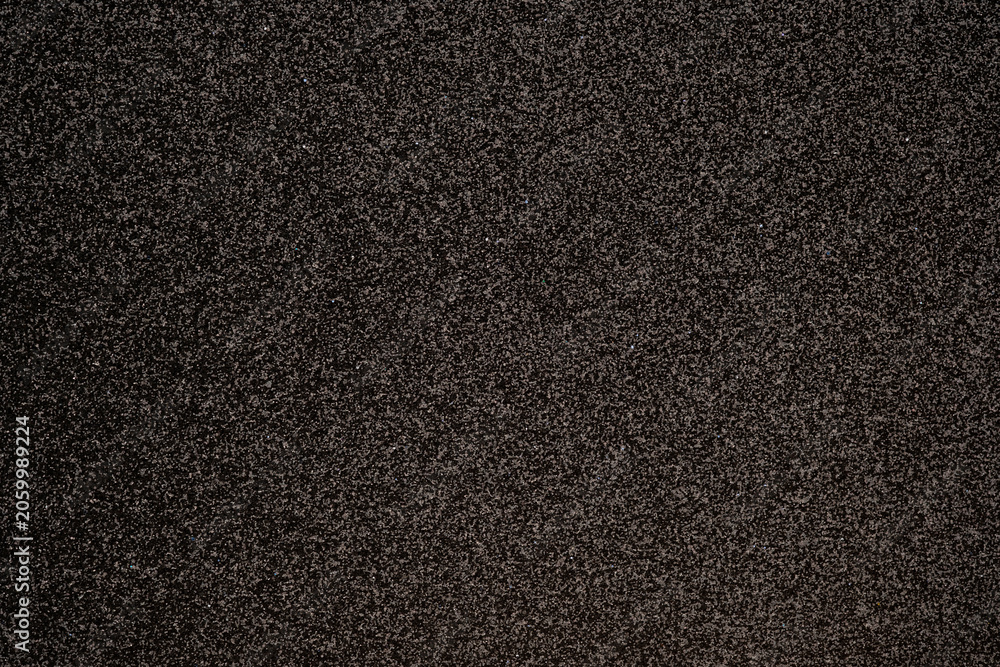 Fototapeta premium Dark textured surface with fine speckles, showing subtle reflective details suitable for backgrounds