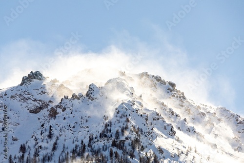 Snow-covered mountain peak with wind