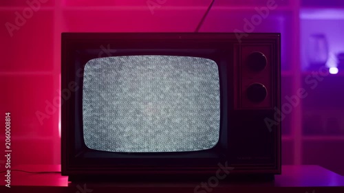 Vintage television displaying static noise in a colorful ambient setting. Represents nostalgia and the evolution of media technology