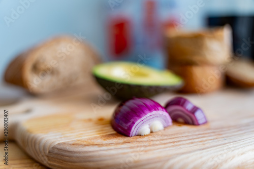 Photos Chopped purple onion on wood chopping block with fresh organic avocado and crust
