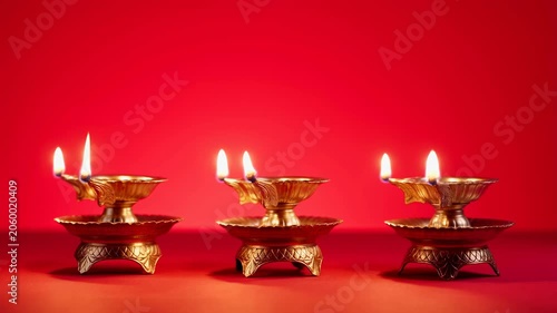 Elegant golden oil lamps with flickering flames against a vibrant red background. Symbolizing light, celebration, and cultural traditions