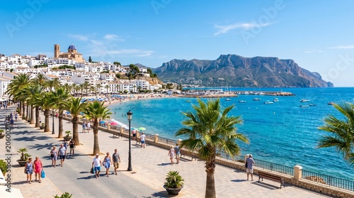 Altea town embankment promenade with palm trees on Costa Blanca coast, coastline Altea bay Mediterranean Sea with azure water, mountain range on horizon in sunny summer day, Alicante province, Spain
