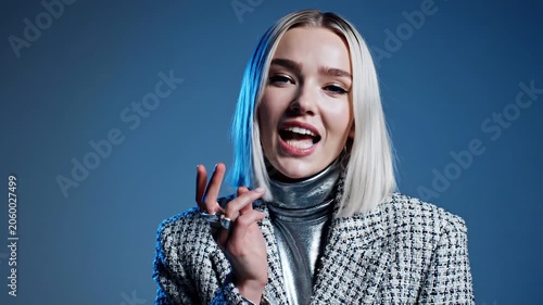 Caucasian woman talking and gesturing in studio. Fashionable lady in metallic turtleneck and tweed jacket expressing opinion or storytelling during video interview.