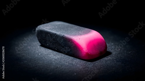 A dual-colored eraser fading from deep black to neon pink in dramatic spotlight, a powerful metaphor for deleting mistakes and revealing a vibrant new beginning.