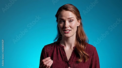 Woman talking to camera. Professional speaker explaining business strategy in blue studio. Interview segment with girl gestures during presentation session.