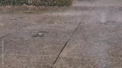 4K Sprinklers Spraying Water on Pavement Refreshing Cooling Motion Outdoor Irrigation Zen Background Commercial Footage