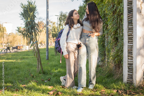 Mother with teenager walk together on a sunny day in the park while enjoying each other's company and sharing smiles