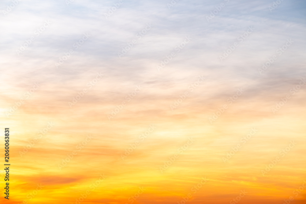 Naklejka premium Sky sunset,Beautiful sunrise sky with vibrant gradient orange and gold colors and soft blue, Clear atmosphere with wispy clouds. Peaceful, perfect for background and copy space, High resolution images
