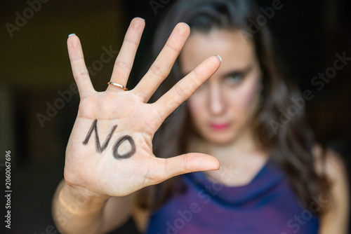 Canvas-taulu Person holding up hand with 'NO' written on it, blurred background