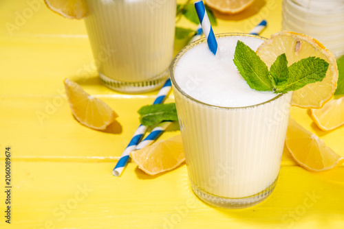 Whipped lemonade or mojito cocktail, lemonade milkshake. Italian summer alcoholic cocktail Sgroppino. Viral Brazilian lemonade. Two servings in glasses and jar, with fresh lemons and mint