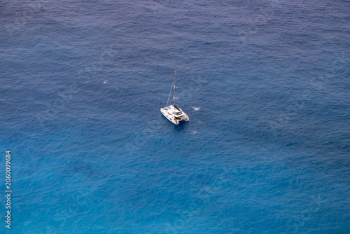 A solo sailing catamaran in the blue sea, seen from above. Greece, Zakynthos Island.