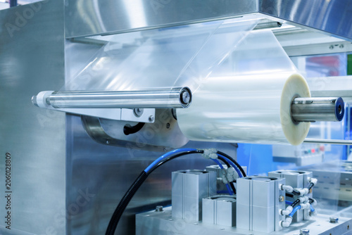 plastic packaging film on the automatic packing machine in food product factory. industrial and technology concept.