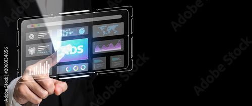 Futuristic Interface Interaction: A person's hand reaches out to touch a glowing, transparent digital screen displaying charts and graphs, embodying advanced technology and data visualization.