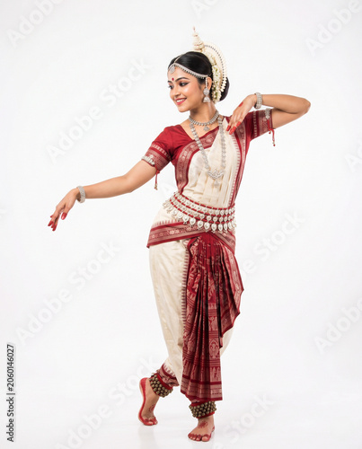 Attractive young Indian woman performing Odissi classical dance in traditional Odisha costume isolated on white background